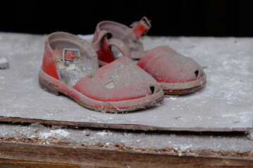 Small red children's sandals in an abandoned kindergarten in Pripyat. Old children's shoes.