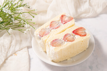 pair of strawberry cream sandwich in white dish on fabric table decarate by plastic flower stock photo