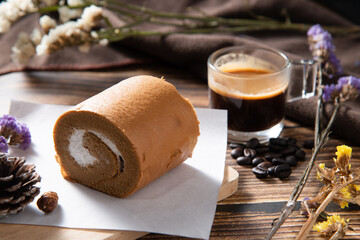 slice coffee roll cake on white rectangle paper and wooden plate with shot of coffee decorate by coffee beans dry flower on wood texture table in morning mood stock photo