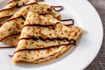 Sweet crepes with chocolate on wooden table.Close up	