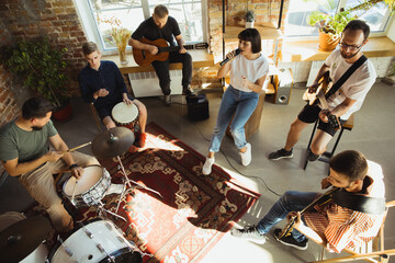 Rhythm. Musician band jamming together in art workplace with instruments. Caucasian men and women,...