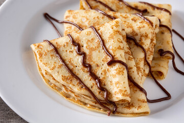 Sweet crepes with chocolate on wooden table.Close up	