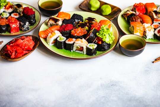 Plates of assorted maki sushi rolls and nigiri sushi on a table
