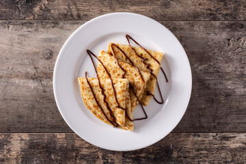 Sweet crepes with chocolate on wooden table.Top view	