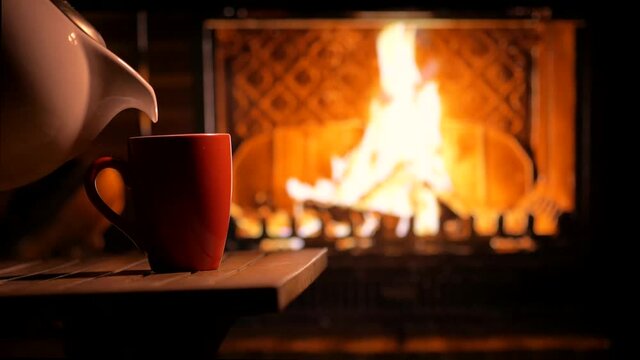 A cup of hot tea in front of the fireplace on a cozy evening. Festive mood