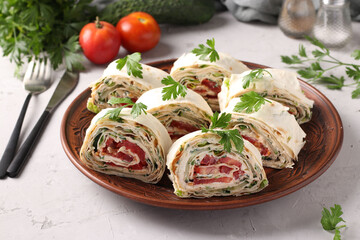 Lavash roll with cucumbers, tomatoes, cheese and parsley on gray background. Holiday appetizer. Horizontal format