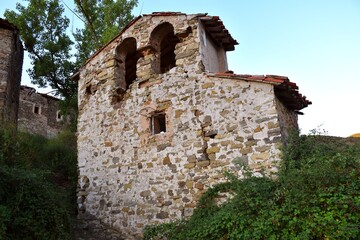 Fototapeta na wymiar Ruins of the church of Santa Ana in Valtrujal with lush vegetation around.