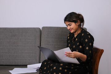 business, people and technology concept - businesswoman with laptop computer and papers working at home