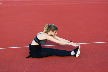 Young, beautiful girl athlete in sportswear is training at the stadium