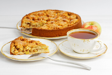 Homemade apple and cinnamon pie and cup of tea on white wooden table. Shallow focus.