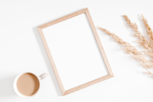 Autumn creative composition. Photo frame, Beige reeds branches bouqueton, cup of coffee white background. Fall concept. Autumn background. Flat lay, top view, copy space