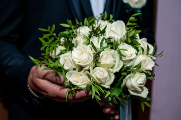 bouquet with white roses in the hands of the groom