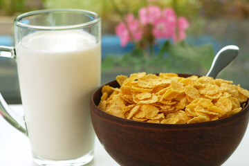 cornflakes in a plate and a glass of milk