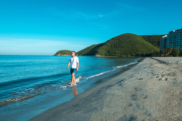 Latino man in mask walking on the beach during the COVID-19 pandemic