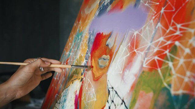Hand of unknown female painter is drawing a portrait on canvas, creating multicolored picture in concept art style