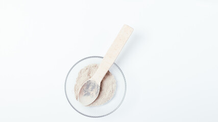 Cosmetic clay with wooden spoon on white table