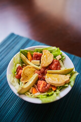 Ensalada de lechuga con tomates, pollo, palta, queso, zanahoria y queso. Vinagreta dulce. Fondo de textura turquesa