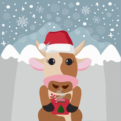 A Christmas bull wearing a Santa hat and holding a Cup looks straight into the woods in winter. Christmas card. Bull and behind the mountains and snowflakes
