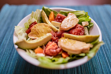 Ensalada de lechuga con tomates, pollo, palta, queso, zanahoria y queso. Vinagreta dulce. Fondo de textura turquesa
