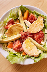 Ensalada de lechuga con tomates, pollo, palta, queso, zanahoria y queso. Vinagreta dulce. Fondo de textura de madera