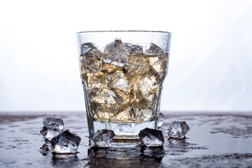 A glass of whiskey with ice is on the bar.