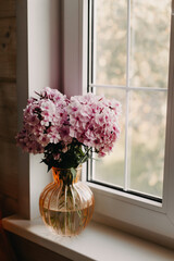 Vase with pink flowers on the cottage window.