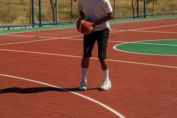 Young man on basketball court dribbling with ball