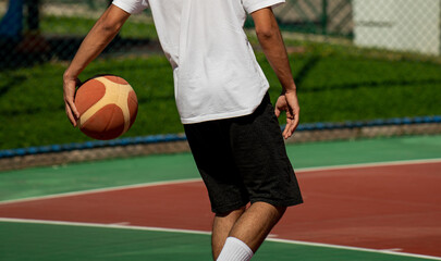 Young man on basketball court dribbling with ball