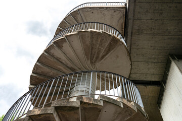 Fototapeta premium Concrete spiral staircase with metal handrails for pedestrian traffic to the bridge.