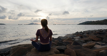 Woman do yoga and sit at seaside