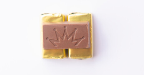 .Chocolate wrapped in gold paper, close-up of a few ounces of chocolate. On a white background