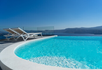 Lounge chair and pool over Santorini caldera. Akrotiri, Santorini island, Cyclades, Greece, Europe. Luxury concept