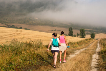 Two women hiking along the Camino de Santiago in Northern Spain with fog moving in.