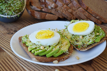 Tasty sandwich with egg, avocado and vegetables on wooden background