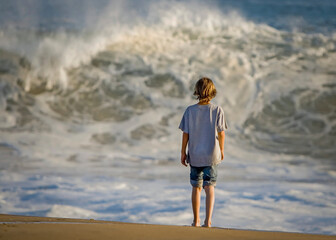Boy standing looking at high surf at Newport Beach CA