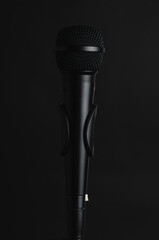 micrófono color negro en un pie de microfono con fondo negro liso