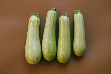 top view harvest of four  zucchini on a brown background