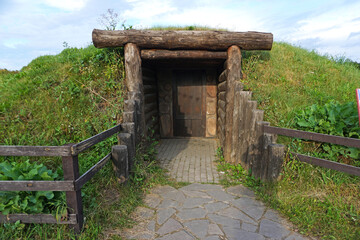 Dugout (or dug-out, pit-house, earth lodge, cellar dug) from logs in autumn fores