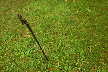 The metal bayonet from Mosin's rifle is stuck in the ground, green grass.End the war