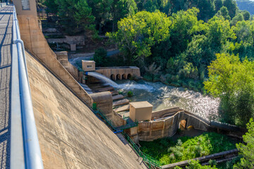 View of the Regajo reservoir dam with a stream of water surrounded by pine forest
