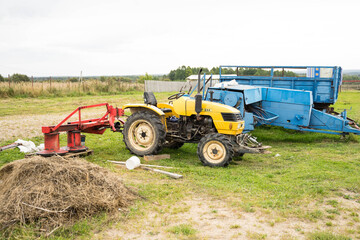 yellow tractor with red bucket stands on the grass