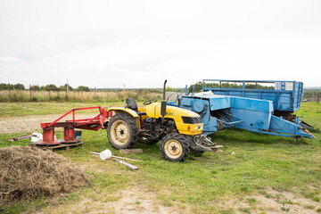yellow tractor with red bucket stands on the grass