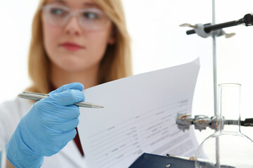 Female chemist in the laboratory of biological analysis portrait doing notes on paper results