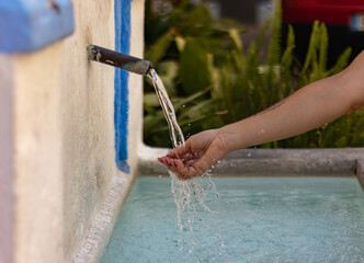Mano de mujer sintiendo la frescura del agua de una fuente con agua fresca y pura