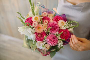beautiful fresh cut bouquet of mixed flowers in woman hand. the work of the florist at a flower shop. Bright juicy red colors