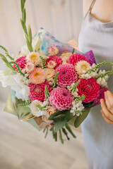 Very nice young woman holding a beautiful blossoming flower bouquet of fresh 
dahlias and roses