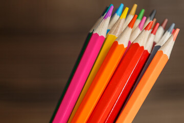 Pens and pencils in metal holder in front of wall background