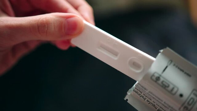 Female hand removing pregnancy test indicator examination closeup from packet