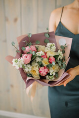 Young florist woman holding freshly made blossoming flower bouquet