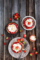 Strawberry meringue tartlets on wooden rustic background